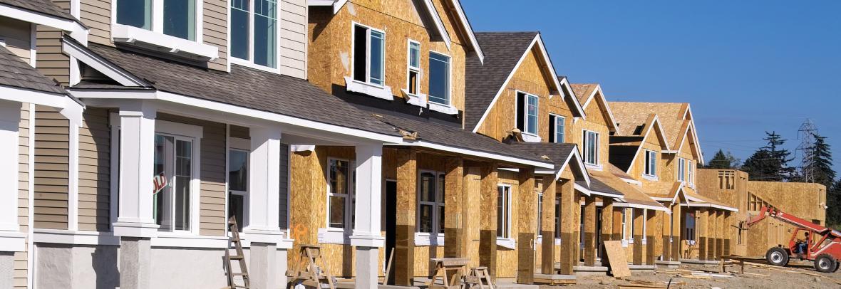 Row of newly constructed houses with exposed wooden frames and windows.